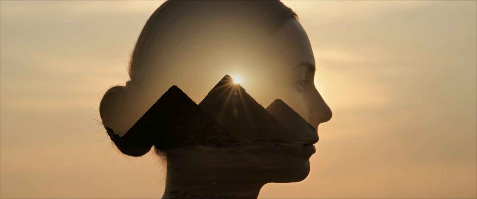 A silhouette of a woman's profile with the Giza pyramids at sunset inside it